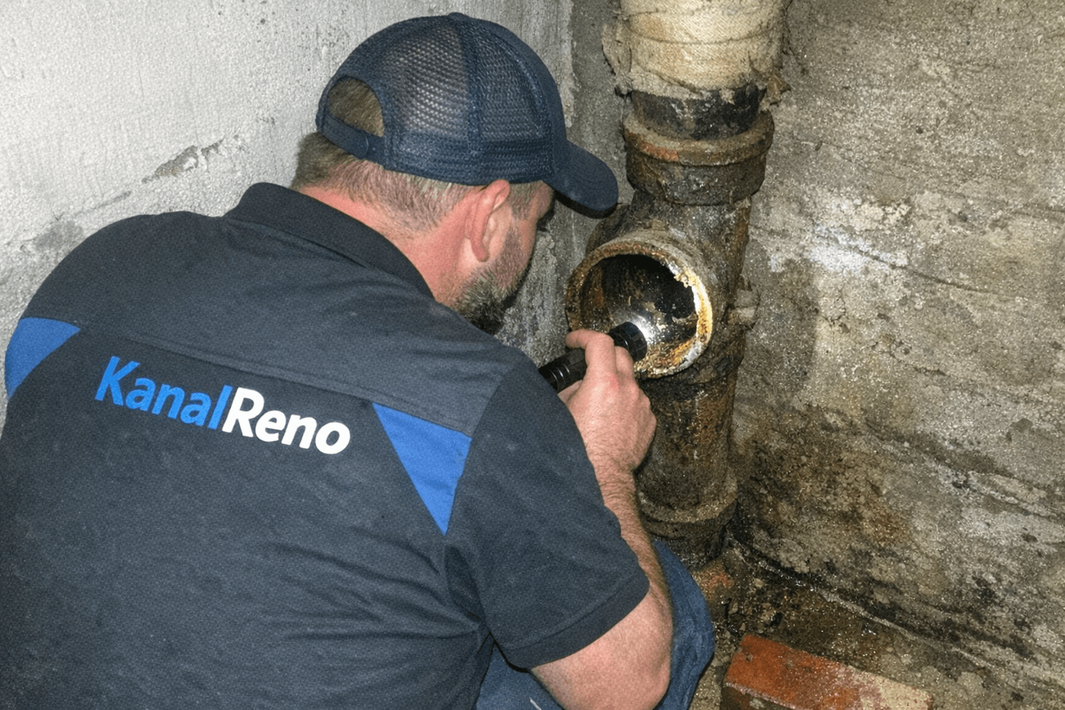 Techniker notiert Messwerte neben geöffnetem Revisionsverschluss im Keller